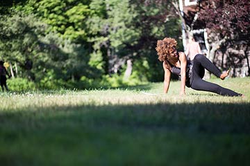 student doing the cat on the grass surrounded by trees